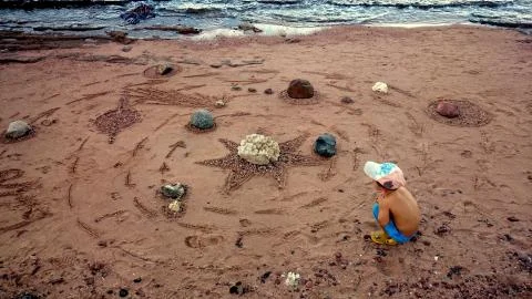 Boy makes a model of the solar system in the sand Stock Photos
