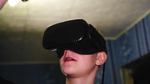 The boy makes movements with game controllers with a virtual reality helmet Stock Footage 145674882