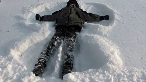 Boy making an angel in the snow Stock Footage 237478893