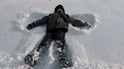 Boy making an angel in the snow Stock Footage 237479046