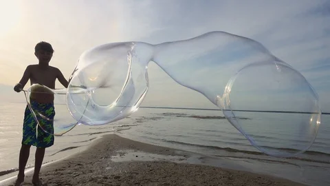 Boy making big soap bubbles on the beach Stock Footage 86592426