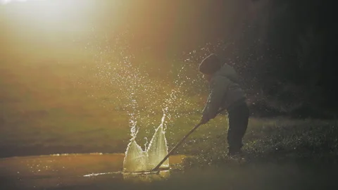 Boy making drops splash with a stick Stock Footage 254004310