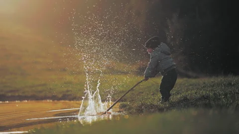 Boy making drops splash with a stick Stock Footage 254004358