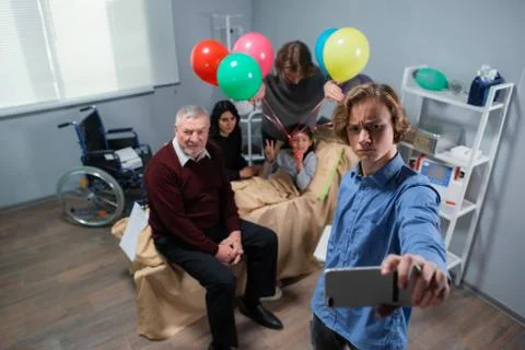 A boy is making faces while taking a selfie with his sick little sister and the Stock Photos