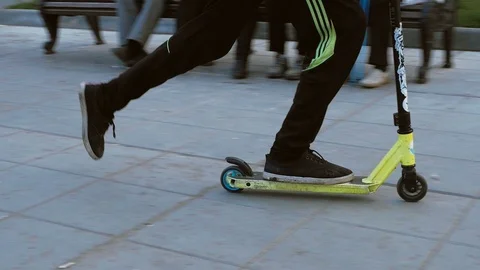 A boy is making a feat on his scooter in a summer park. Stock Footage 117930307