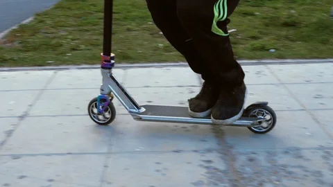 A boy is making a feat on his scooter in a summer park. Stock Footage 117930381