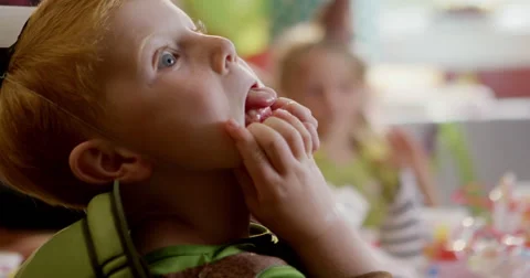 Boy making funny faces during a birthday party Stock Footage 58573767