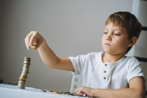 Boy making pyramide of coins. ABC of finance. boy counting money Stock-Fotos