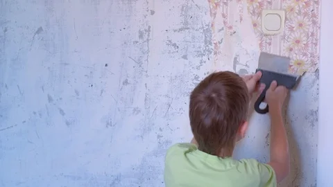 Boy is making renovation removing wallpapers from wall, construction work. Video stock 124948119