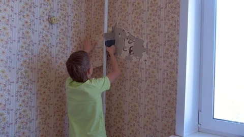 Boy is making renovation removing wallpapers from wall, construction work. Stock Footage 124948749