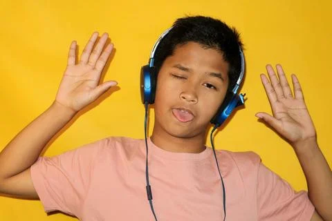 A boy is making a silly face while wearing headphones. Stock Photos
