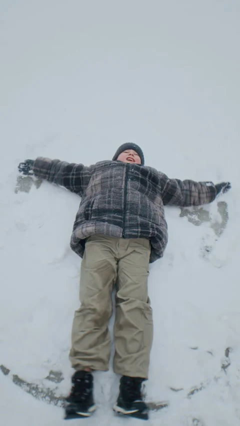 Boy Making Snow Angel Outdoors Stock Footage 321285326