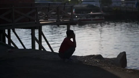 A boy man waiting and river side with evening sunset behind Stock-Footage 136563349