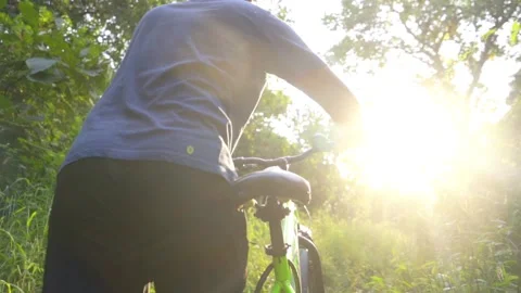 Boy man walking  toward the sun with a cycle in deep jungle slow motion Stock Footage 142168505