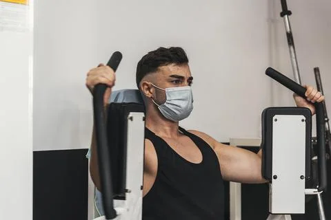 Boy with mask doing chest exercise in gym Stock Photos
