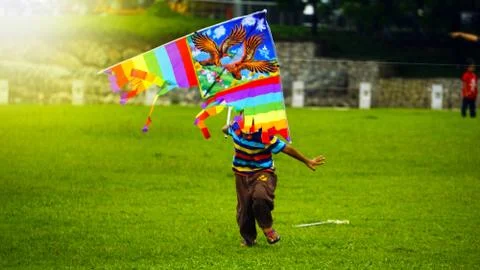 Boy with mask flying a kite at a park. Boy holding a colorful kite standing o Stock Photos