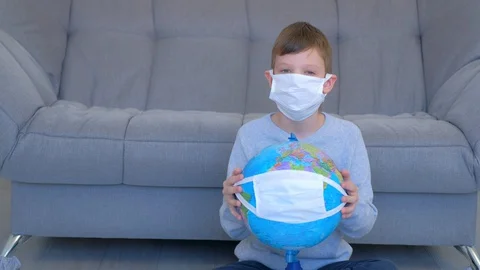 Boy in mask holding globe in mask in hands, coronavirus pandemic and quarantine. Stock Footage 128945754