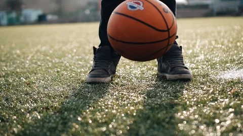 A boy mints a basketball on the grass. Close up. Beautiful light. Sports warm-up 스톡 동영상 125856844