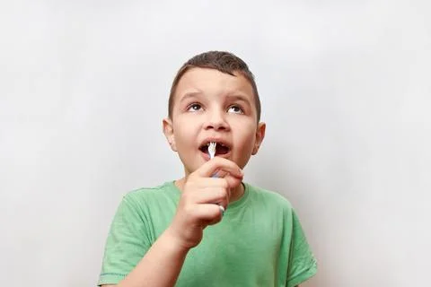 A boy with missing baby teeth uses a toothbrush. Baby teeth care. Stock Photos