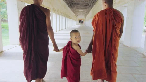Boy monk looking back wile walking in ancient passage way of temple in Bagan Mya Stock Footage 201096892