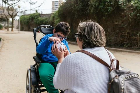 Boy with multiple disabilities playing with a soccer ball with his mother Stock Photos