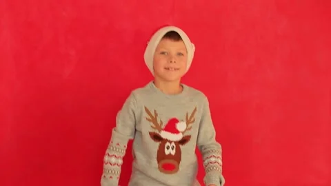 Boy in a New Year's cap and sweater on a red background. Video stock 161136424