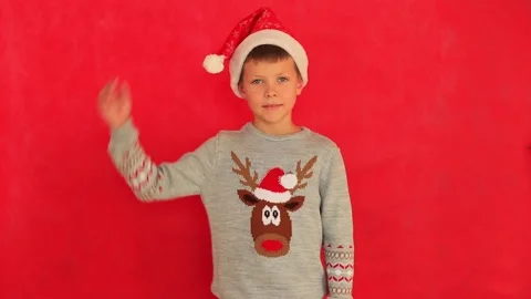 Boy in a New Year's cap and sweater on a red background. Video stock 161533216