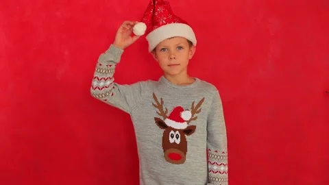 Boy in a New Year's cap and sweater on a red background. Video stock 161950101