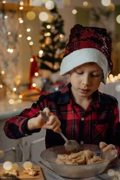 Boy in a New Year's cap preparing christmas gingerbread cookies in the home k Stock Photos