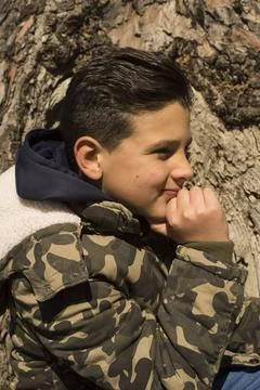 Boy next to a tree trunk. Stock Photos