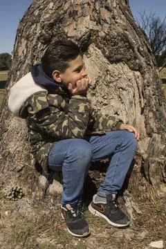 Boy next to a tree trunk. Stock Photos