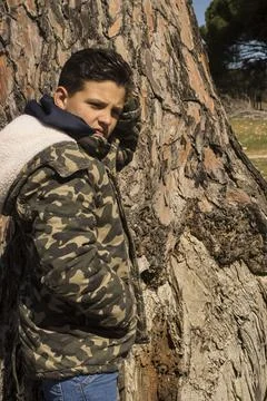 Boy next to a tree trunk. Stock Photos