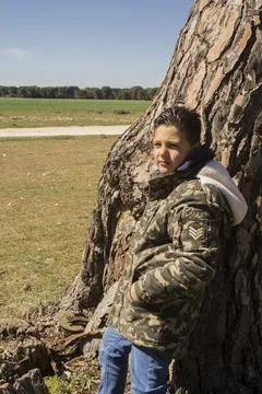 Boy next to a tree trunk. Stock Photos