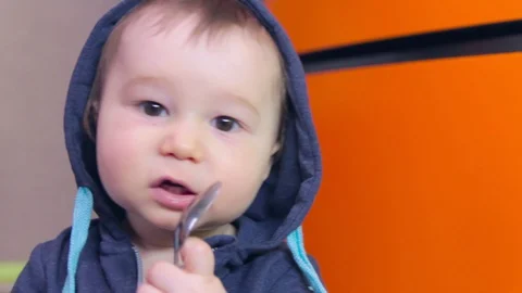 Boy nibbles a spoon at home Stock Footage 129720622