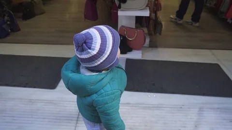 Boy of one year is considering a store. The kid carefully examines the inside of Stock Footage 85037443