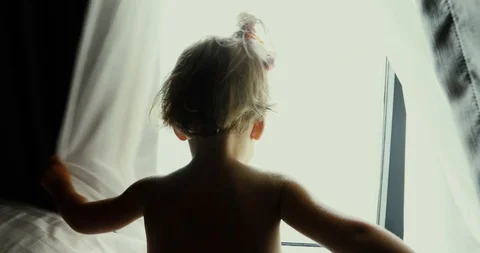 Boy opening the curtain and looking out 動画素材 100175231