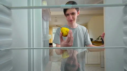 Boy opening empty fridge with rotten pear on shelf, view from inside of fridge Stock Footage 312039940