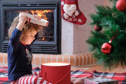 Boy opening gift boxes under christmas tree Foto stock