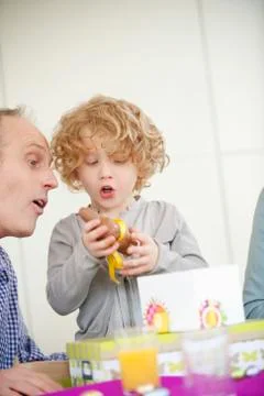 Boy opening his birthday present with his grandfather beside him Stock Photos