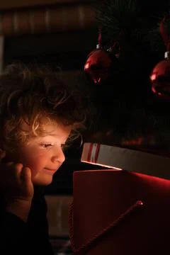Boy opening magic gift box near Christmas tree Stock Photos