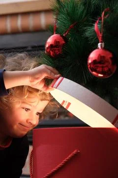 Boy opening magic gift box near Christmas tree Stock Photos