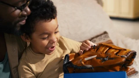 Boy opening present box with baseball glove Stock Footage 100690697
