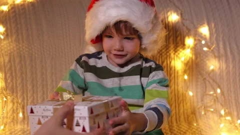 A boy opening present box at holiday lights background. Christmas. Slow Motion Stock Footage 164992822
