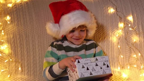 A boy opening present box at holiday lights background. Christmas. Slow Motion Stock Footage 164992885