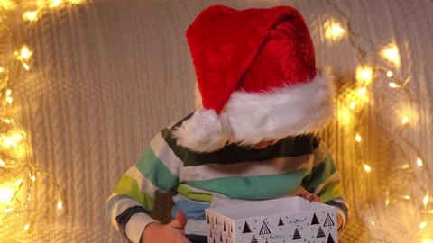 A boy opening present box at holiday lights background. Christmas. Slow Motion Stock Footage 164993026