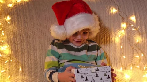 A boy opening present box at holiday lights background. Christmas. Slow Motion Stock Footage 164993181
