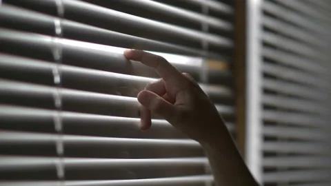 Boy opens the blinds and looks out the window with surprise Stockbeeldmateriaal 94833926