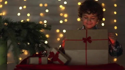 A boy opens a Christmas present and marvels at the magic of Christmas Stock Footage 166980616