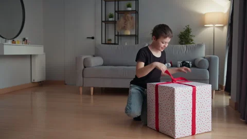 Boy Opens Giant Gift Box. Excited child festive surprise joyful home moment Stock Footage 335479429