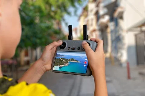 Boy operating a drone while viewing a live aerial feed of a coastal landsca.. Stock Photos